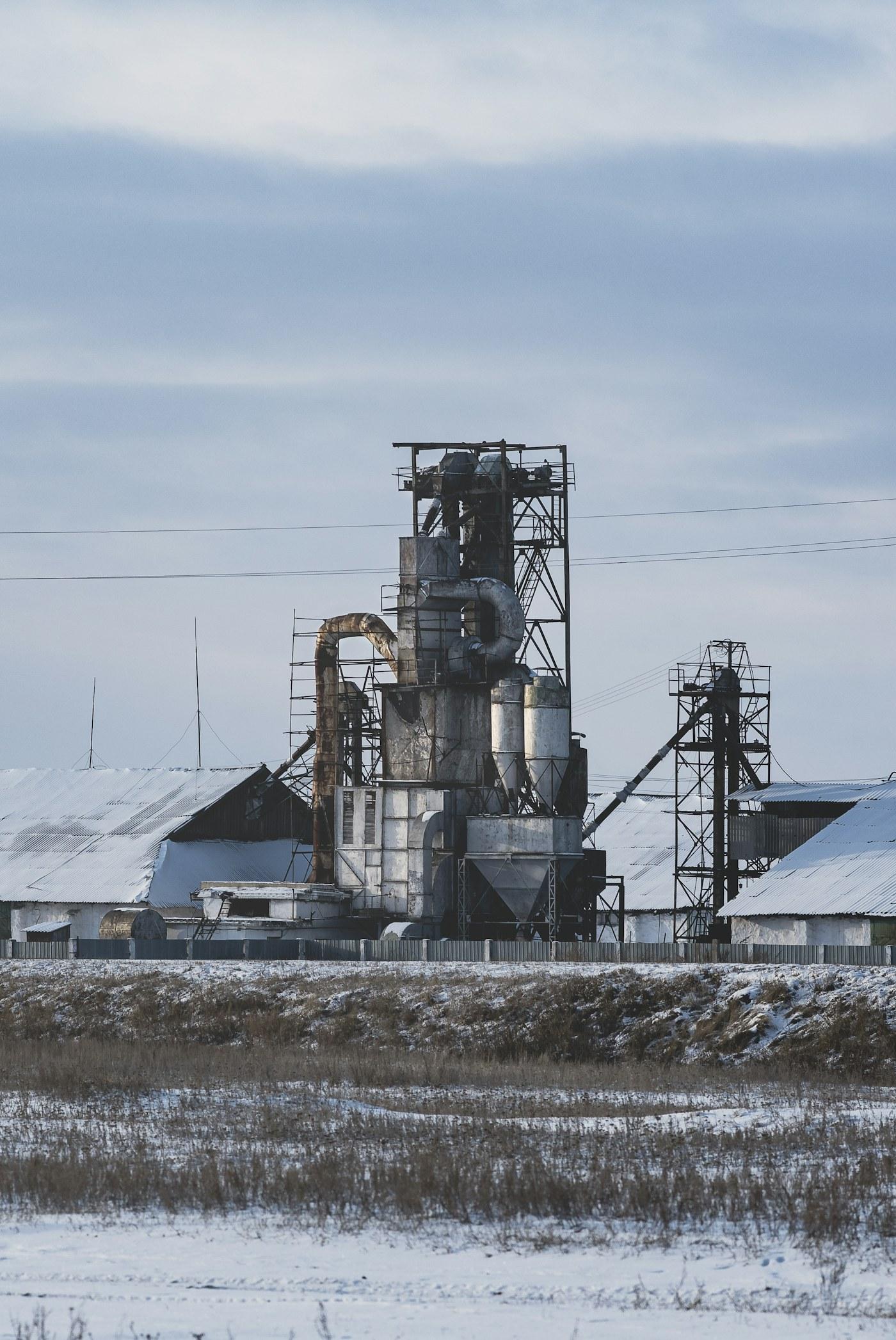 Scène d'industrie lourde dans une aciérie avec des cheminées dégageant de la vapeur et des conduits de surveillance des émissions au-dessus des opérations de coulée lors d'un poste de jour.