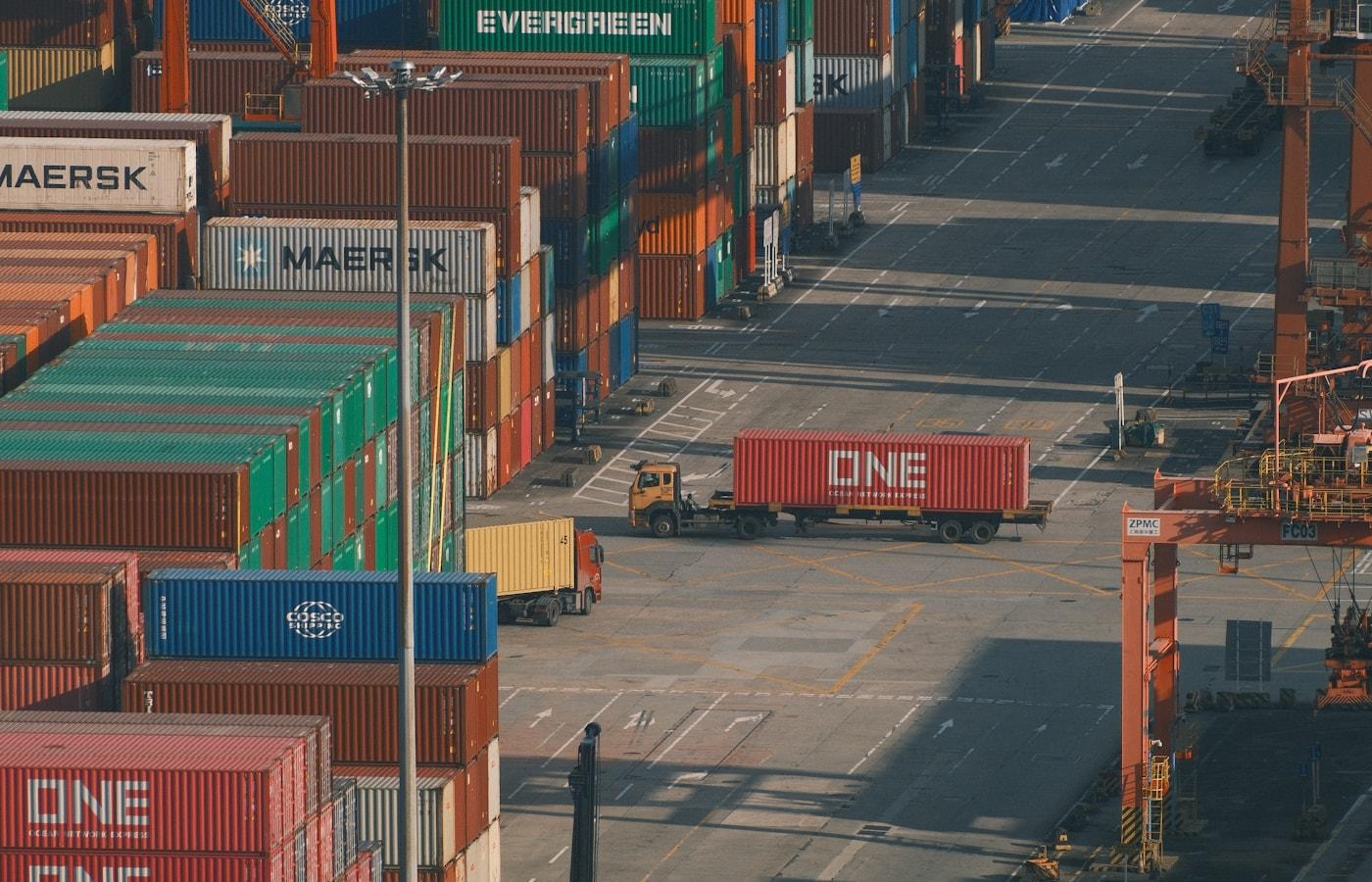 Shipping containers stacked high at a busy container port, awaiting customs clearance and final delivery